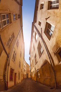 Low angle view of narrow alley amidst buildings in city