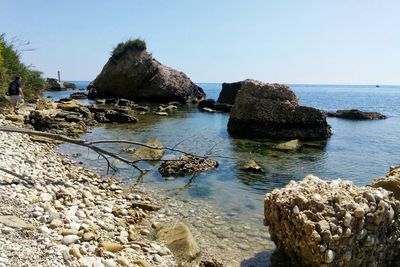 Rocks on sea shore against clear sky