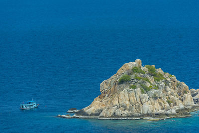 Sailboat on rock by sea against blue sky