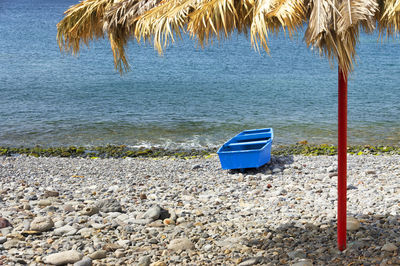 High angle view of blue and parasol on boat on pebbles at shore