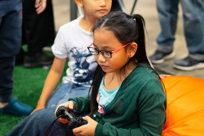 Cute girl playing video game by sister