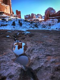 Snow covered rock by buildings against sky