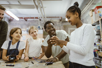 Smiling female teacher assisting female student at technology workshop in school