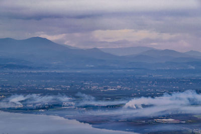 Aerial view of city and mountains against sky