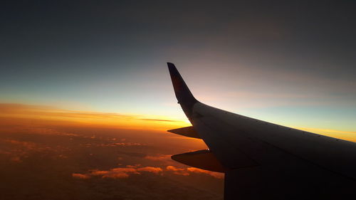 Airplane flying against sky during sunset