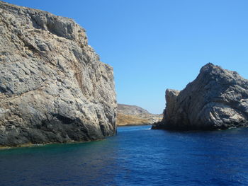 Scenic view of sea and rock formation against clear blue sky