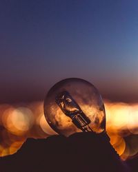 Close-up of a silhouette man holding crystal ball against sky