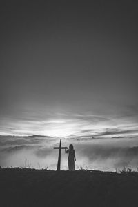 Silhouette man standing on field against sky during sunset