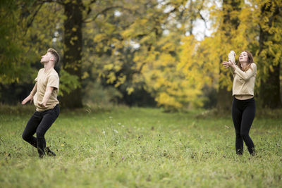 Young couple dancing on grassy field at park