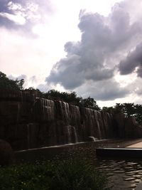 View of waterfall against cloudy sky