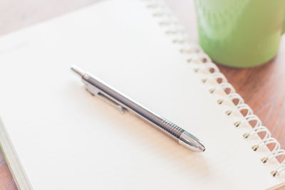 High angle view of pen on book by mug