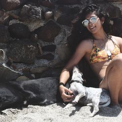 Young woman with dog sitting on sofa at beach