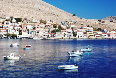 Sailboats moored in sea by town against sky