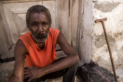 Portrait of man sitting against wall