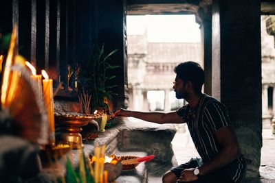 Side view of man holding candles in temple