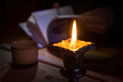 Close-up of burning candle on table in darkroom