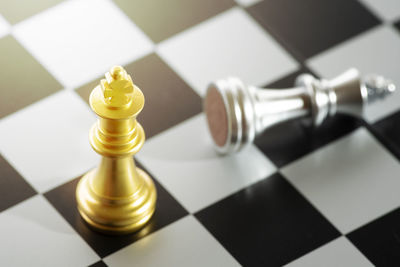 Close-up of golden king defeated silver king on chess board