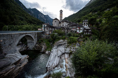 Arch bridge over river amidst buildings against sky