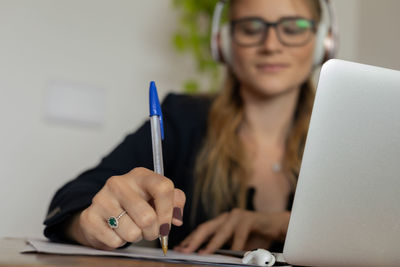 Woman working at home with laptop and papers on desk and headphones. home office . gray notebook 