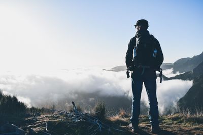 Rear view of man standing on mountain against sky