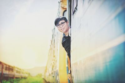 Portrait of smiling young man standing in train