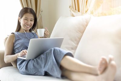 Midsection of woman using mobile phone while sitting on sofa