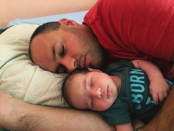 Father and son sleeping on bed at home