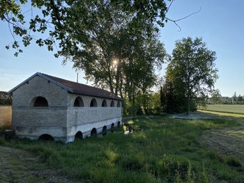 Built structure on field by trees against sky