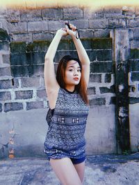 Young woman standing against wall