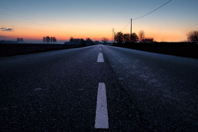 Surface level of road against sky at sunset