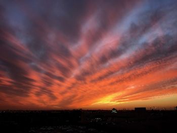 Silhouette cityscape against sky at sunset