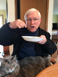 Man eating food while sitting with cat at home