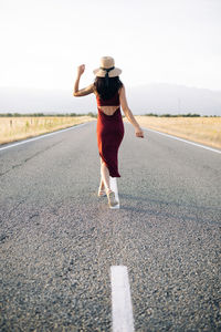 Rear view of woman standing on road against sky