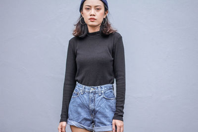 Portrait of woman standing against gray wall