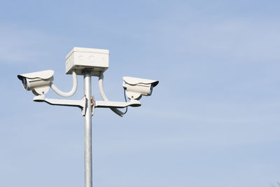 Low angle view of security cameras against sky