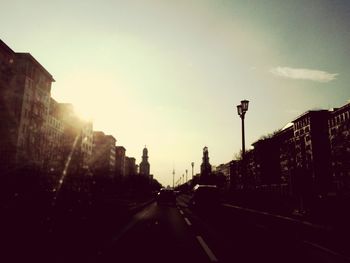 Road passing through city at sunset