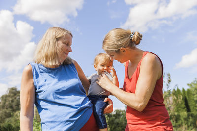 Women looking at daughter against sky