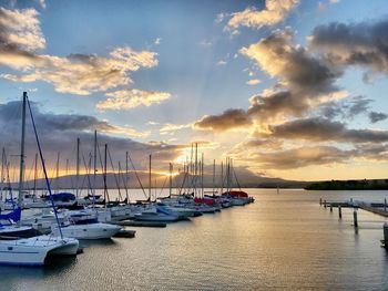 Boats moored at harbor during sunset