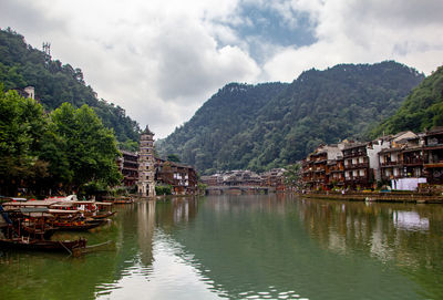 Scenic view of river by buildings against sky