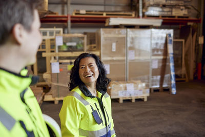 Happy female worker discussing with colleague while walking in distribution warehouse