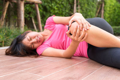 Portrait of young woman lying on pink floor