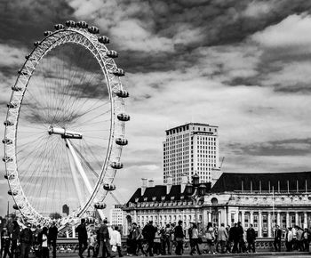 Low angle view of ferris wheel against cloudy sky
