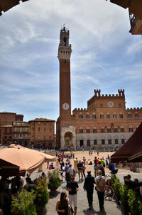 Group of people in front of historical building against sky