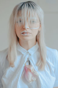 Close-up portrait of woman with painted face against white background