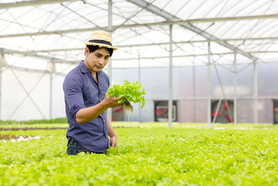 Portrait of smiling young woman standing in greenhouse