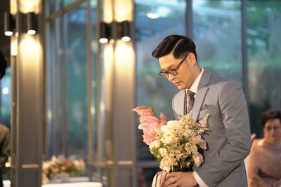 Young man holding flower bouquet against blurred background