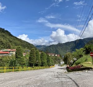 Road by plants and mountains against sky