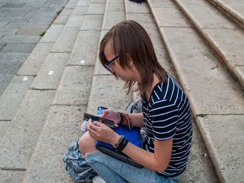 Side view of teenage girl using mobile phone while sitting on steps