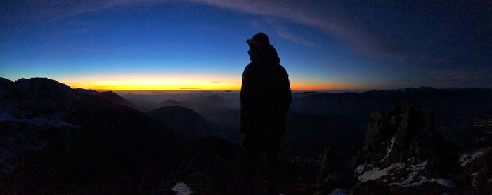 Silhouette man standing on mountain against sky during sunset