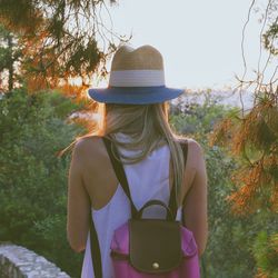 Rear view of woman wearing hat standing against trees